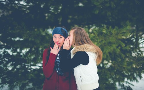 Two friends in the snow whispering secrets to each other | © Unsplash.com