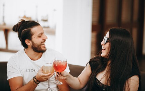 A man and a woman sharing cocktails at a bar | © Unsplash.com
