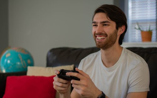 A smiling man playing a video game | © Unsplash.com