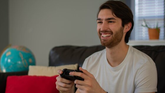 A smiling man playing a video game | © Unsplash.com
